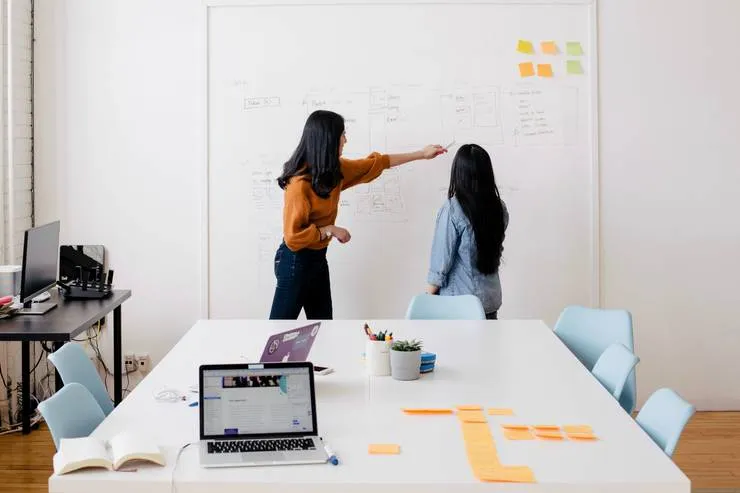 Women discussing in front of a whiteboard